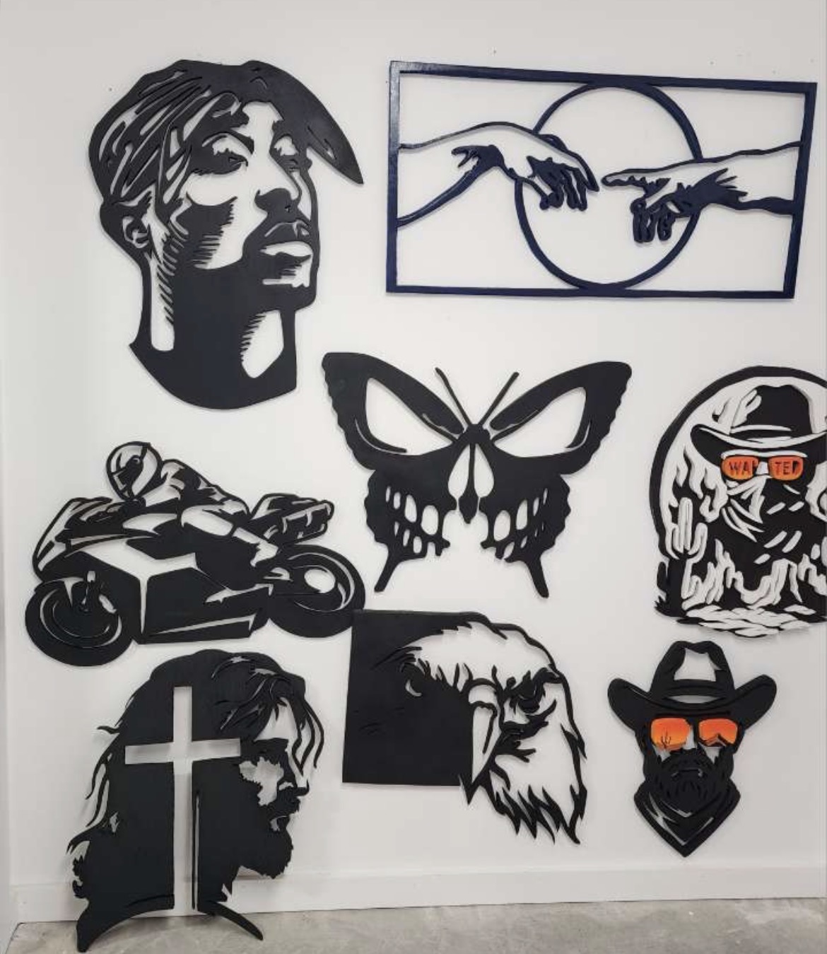 A wall of hand-cut fretwork signs including portraits, a butterfly and a motorcycle