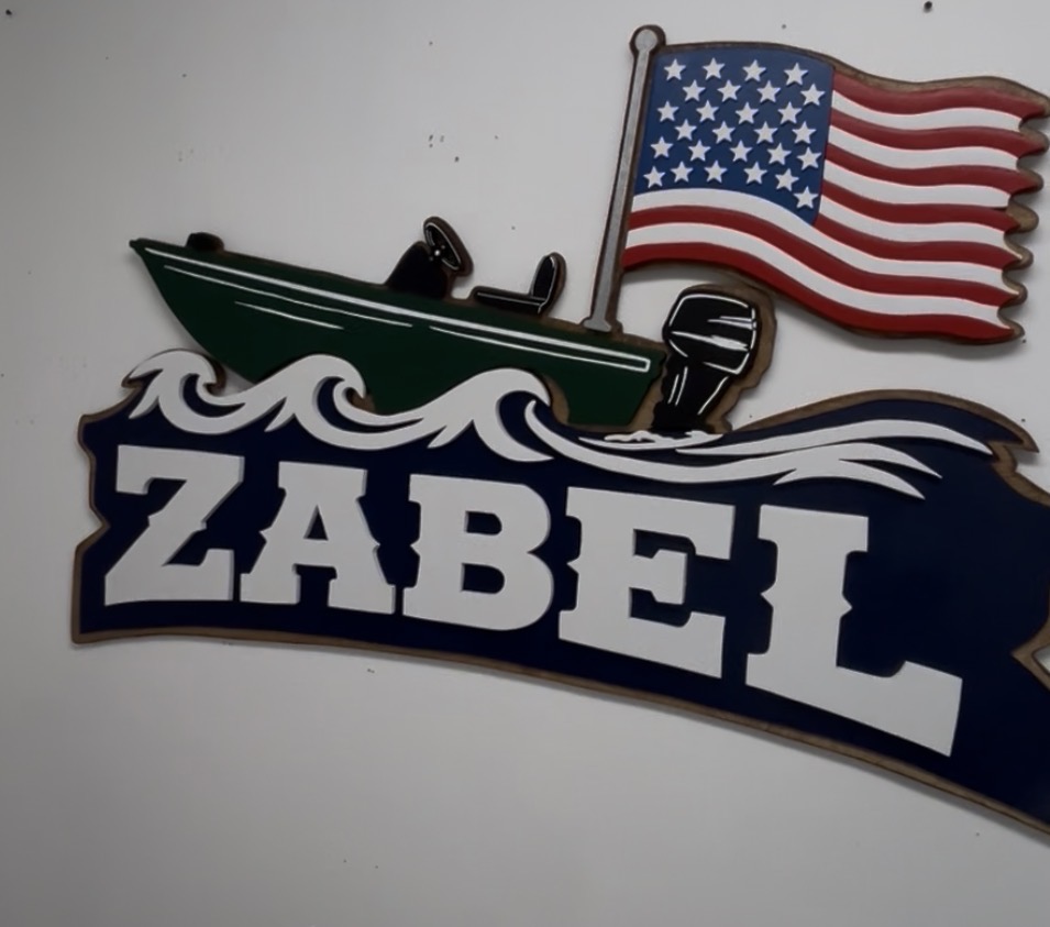 'Zabel' family sign with a hand-cut jon boat and American flag, example of custom handmade wood work